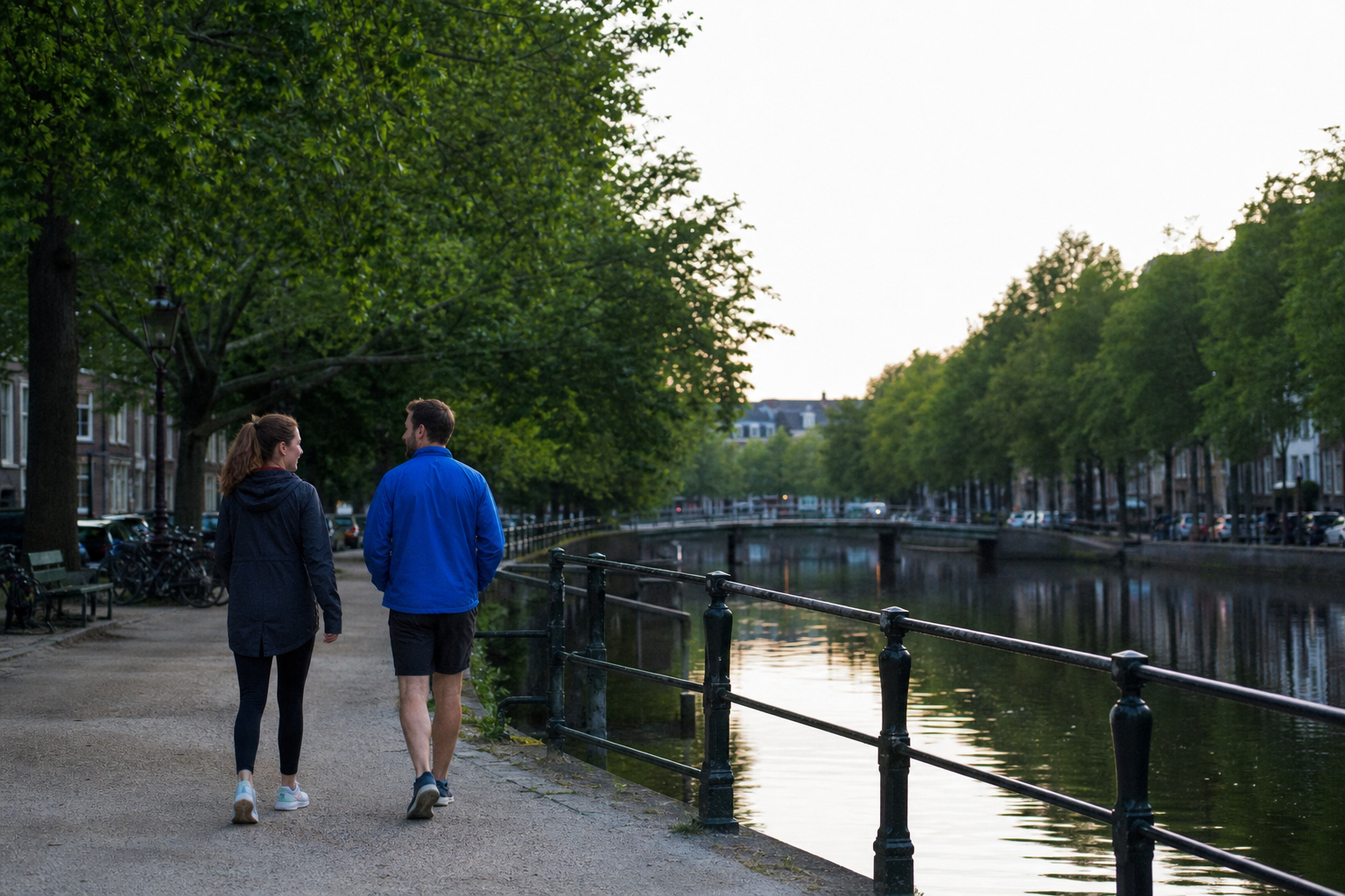 Twee mensen wandelen in de avond langs een rustige stadsgracht